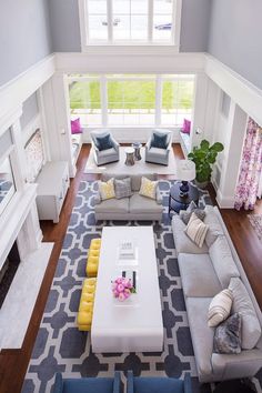 an aerial view of a living room with gray couches and yellow accent pillows on the rug