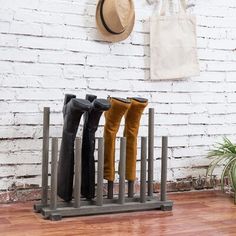 four pairs of boots are lined up on a rack in front of a white brick wall