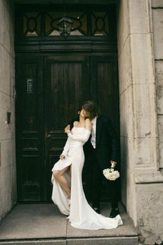 a bride and groom kissing in front of a door