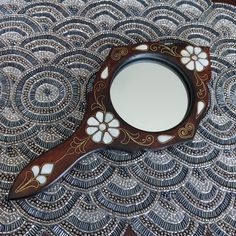 a mirror sitting on top of a table next to a flowery pattern covered surface