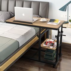 an open laptop computer sitting on top of a wooden desk in front of a bed