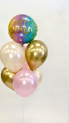 a bunch of balloons with the words happy birthday written on them in gold, pink, and blue