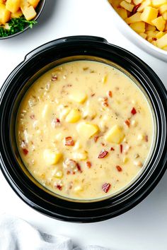 there is a bowl of soup with potatoes in it and other bowls around it on the table