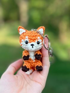 a small crocheted fox keychain is being held in someone's hand