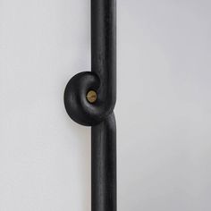 a black door handle on the side of a white wall with a round hole in it