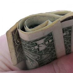 a person's hand holding three stacks of one hundred dollar bills