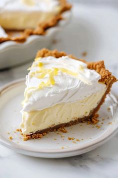 a slice of lemon pie on a plate with the rest of the pie in the background