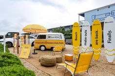 a yellow and white food truck parked in front of a building with surfboards on display