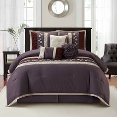 a bed with purple comforter and pillows in a room