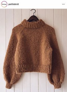 a brown sweater hanging on a white wall