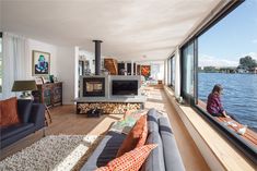 a woman sitting on a couch in front of a window looking out at the water