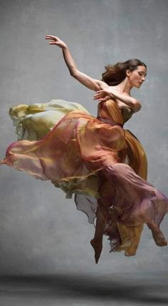 a woman in a flowing dress is dancing