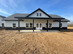 a white and black house sitting on top of a dry grass field