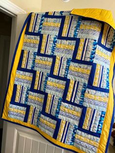 a blue and yellow quilt hanging on the wall