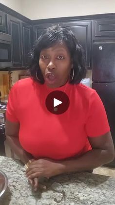 a woman in a red shirt making a funny face while sitting at a kitchen counter