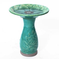 a green ceramic pedestal with flowers on it