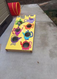 a yellow board game with teapots and cups painted on it sitting in front of a house