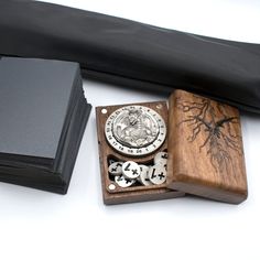 a wooden box with some stamps in it next to a black bag on a white surface