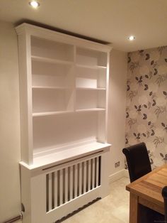 an empty room with a desk and bookcase in the corner, next to a wallpapered wall