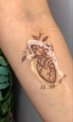 a tattoo on the arm of a woman with a heart and flowers painted on it