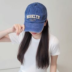 a woman wearing a blue hat with the word brooklyn on it, sitting at a table