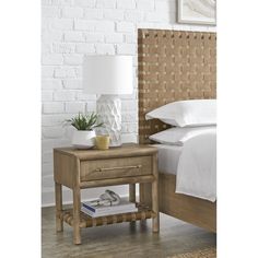 a nightstand with a lamp on it next to a bed