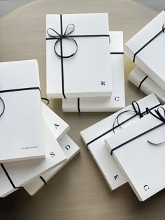 four white gift boxes tied with black ribbon on a round table, one is empty and the other has a ring