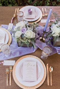 the table is set with purple napkins and gold place settings for an elegant dinner