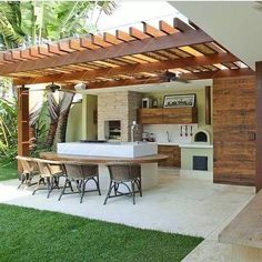 an outdoor kitchen and dining area is shown in this backyard setting with wood pergolated roof