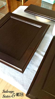 two brown cabinets sitting on top of a wooden floor next to a white table cloth