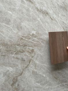 a person holding a wooden object on top of a marble floor