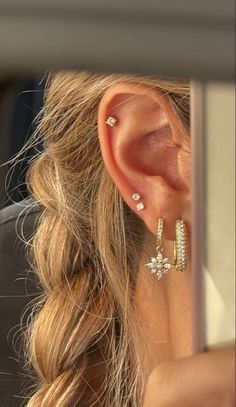 a woman wearing gold ear cuffs and earrings