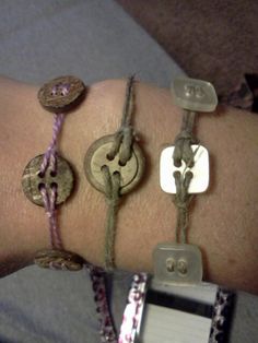 three different bracelets on someone's arm, one with buttons and the other with charms