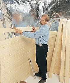 a man standing in front of a wall with wood planks on it and another person holding a piece of plywood