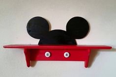 a mickey mouse head is mounted on a red shelf with two black ears that are plugged into the outlets