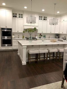 a large kitchen with white cabinets and wooden flooring, along with an island in the middle