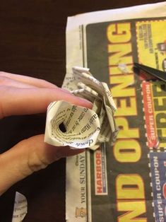 a person holding a rolled up newspaper with scissors on it and paper tape around the edge