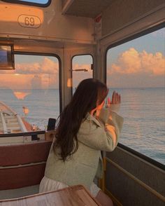 a woman sitting at a table in front of a window looking out on the ocean