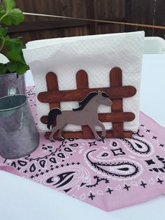 a small wooden horse standing on top of a table next to a potted plant