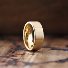 a gold wedding ring sitting on top of a wooden table