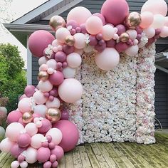 pink and white balloons are on the back of a house