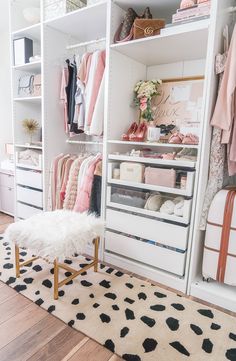 a white closet filled with lots of clothes and other items on top of shelves next to a rug