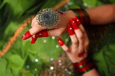 a woman's hand with red fingernails and green ring