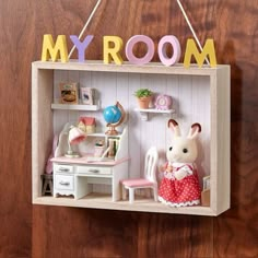 a toy room with a desk, chair and bunny doll hanging from the wall next to it