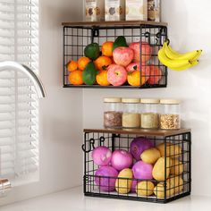 two metal baskets filled with fruits and vegetables on top of a wall next to a window