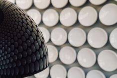 a black and white lamp is in front of many plates on the wall behind it