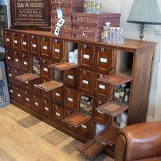 a large wooden cabinet filled with lots of drawers next to a leather chair and lamp