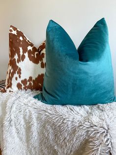 two pillows sitting on top of a bed next to each other in front of a white wall