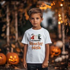 a young boy wearing a monster mash t - shirt in front of pumpkins