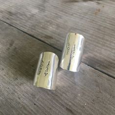 two silver rings sitting on top of a wooden table